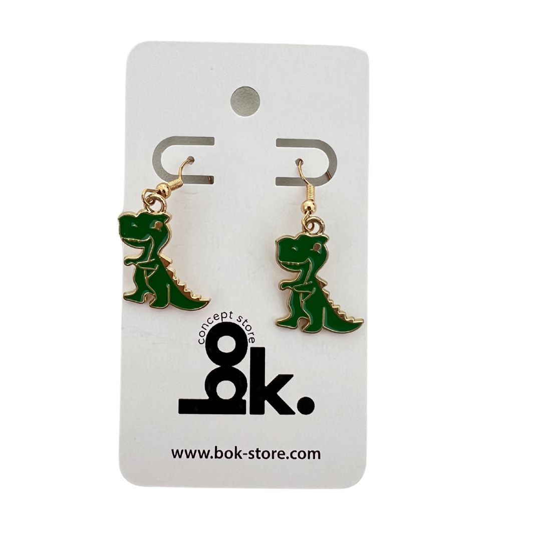 Aretes Freak Dinosaurios Rex en color verde con detalles dorados. Un accesorio divertido, llamativo y lleno de personalidad para los amantes de los dinosaurios