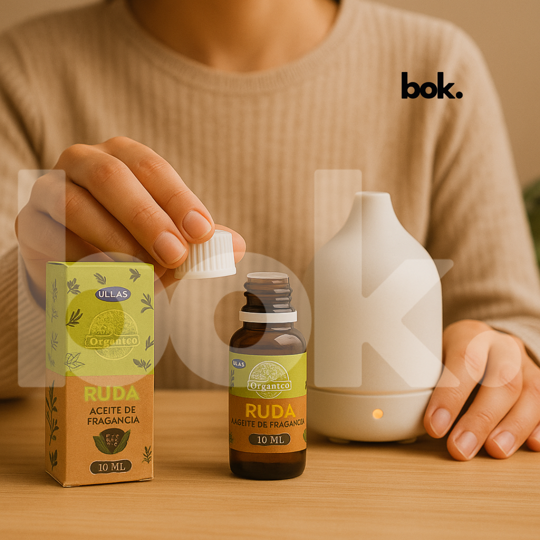 Aceite Natural de Ruda de BOK Concept Store junto a un difusor de aromaterapia sobre mesa de madera, estilo lifestyle e-commerce, ambiente cálido y relajante.