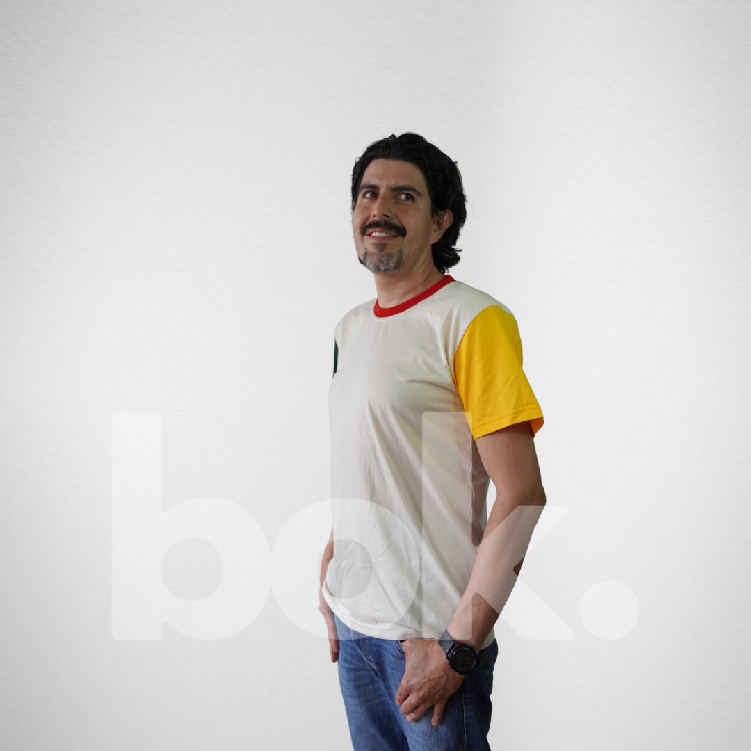 Modelo luciendo una camiseta retro beige con detalles en amarillo, verde y rojo, combinada con jeans para un look casual y relajado.