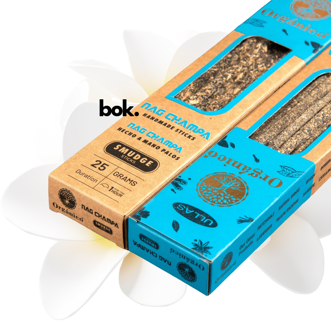 Incienso Nag Champa artesanal BOK, caja azul y kraft de 25 gramos hecha a mano en la India, sostenida por una mano sobre fondo neutro, producto natural para meditación y yoga.