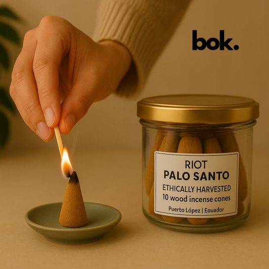 Persona usando un cono de incienso de Palo Santo de BOK Concept Store, con frasco de vidrio y ambiente cálido estilo lifestyle.
