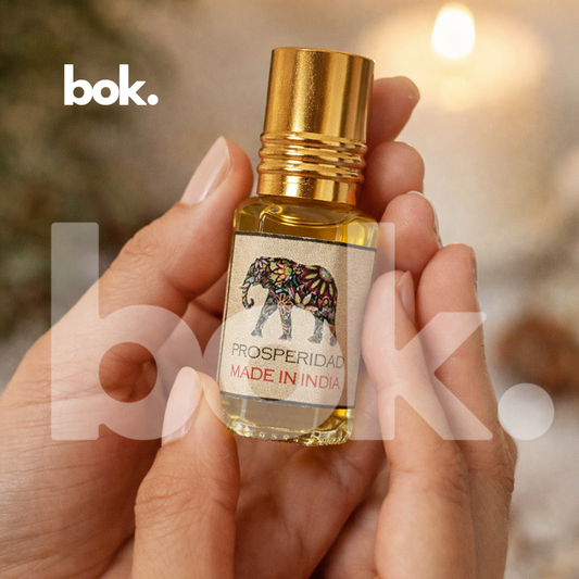 aceite roll on de prosperidad de BOK Concept Store sostenido en manos en ambiente elegante, frasco pequeño con tapa dorada y diseño de elefante simbolo de abundancia y buena suerte