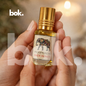 aceite roll on de prosperidad de BOK Concept Store sostenido en manos en ambiente elegante, frasco pequeño con tapa dorada y diseño de elefante simbolo de abundancia y buena suerte