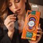 Persona elegante disfrutando chocolate dark 70% con uvilla, menta y nibs de cacao, experiencia sensorial fresca y consciente en estilo lifestyle premium de BOK Concept Store