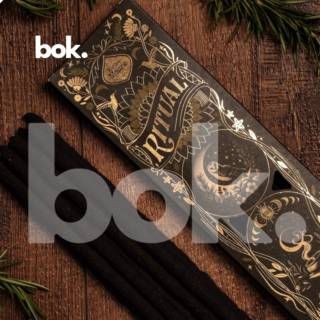 incienso de limpieza energetica de BOK Concept Store con varillas visibles junto a su empaque negro y dorado en composición lifestyle sobre mesa de madera con elementos naturales