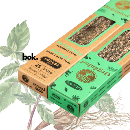 Incienso Patchouli artesanal BOK, caja color marrón-terracota de 25 gramos hecha a mano en la India, sostenida por una mano sobre fondo neutro, producto natural para meditación y bienestar.