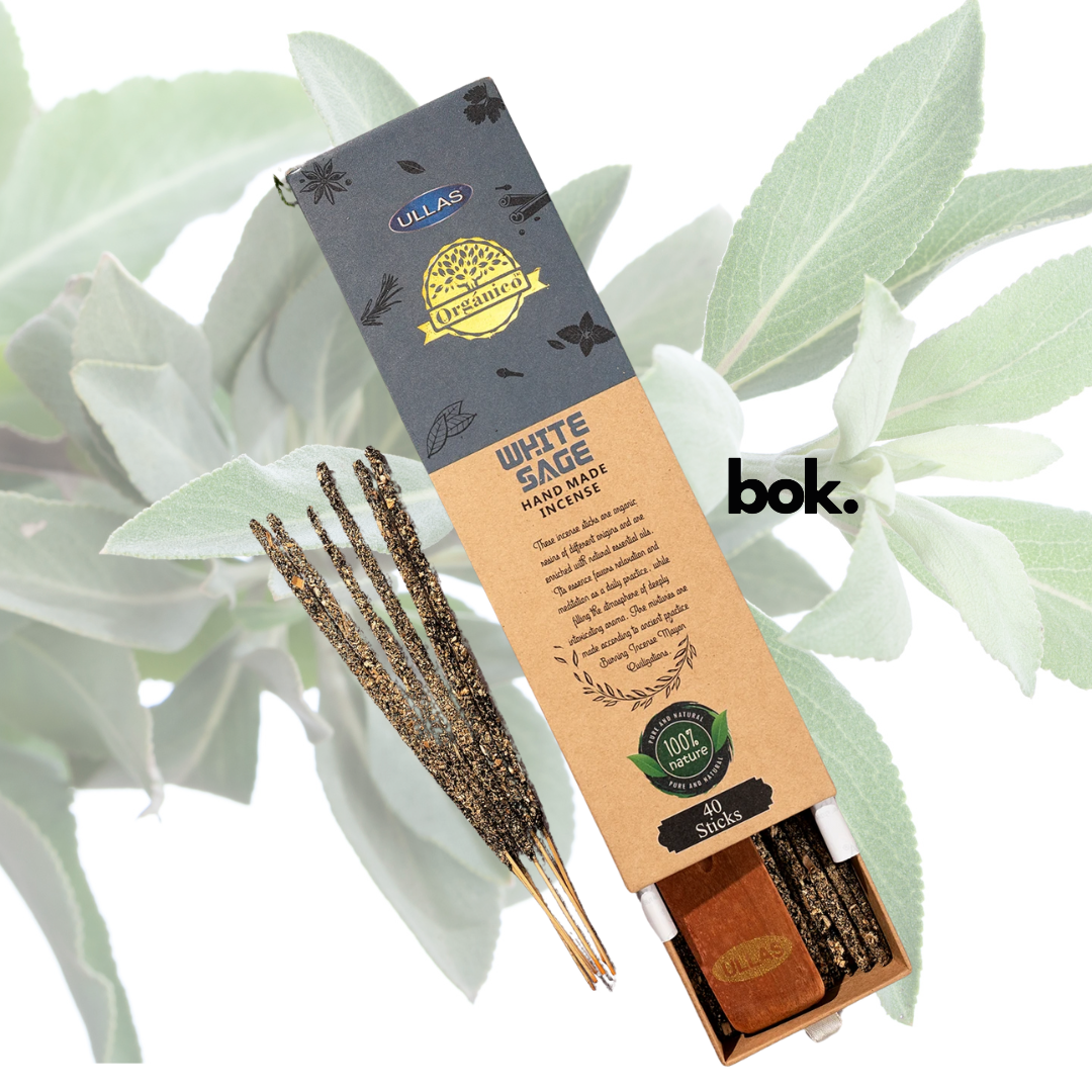 Varilla de incienso de salvia blanca encendida, liberando humo purificador en un ambiente de calma y limpieza energética.