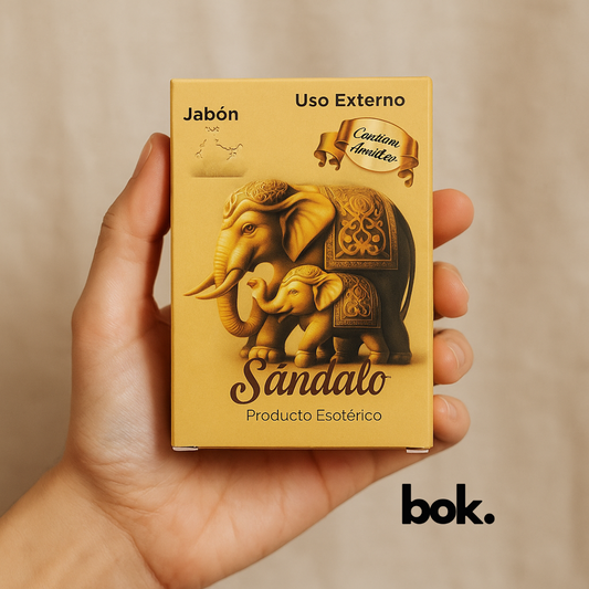 Jabón de sándalo artesanal BOK con amuleto, en caja dorada con diseño de elefantes, sostenido por una mano sobre fondo neutro.