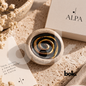 Piedra antiestrés Worry Stone ALPA de cerámica artesanal con espiral negra y dorada. Accesorio de bolsillo para acompañar momentos de tranquilidad y mindfulness, disponible en BOK Concept Store Ecuador.